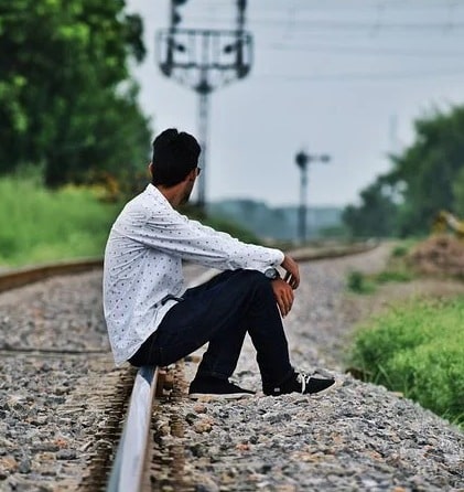 sad boy sitting on railway track dp